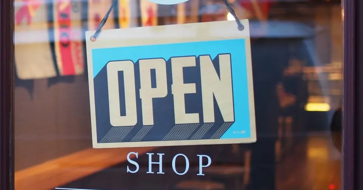 تابلوی OPEN SHOP پشت شیشهٔ یک فروشگاه